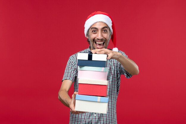 Front view young male holding presents on red background