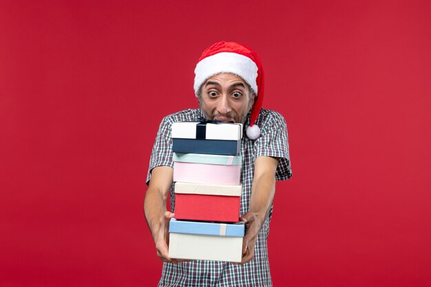 Front view young male holding presents on red background