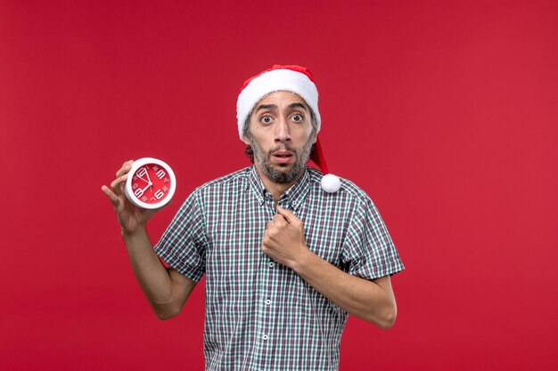 Front view young male holding round clocks on red background