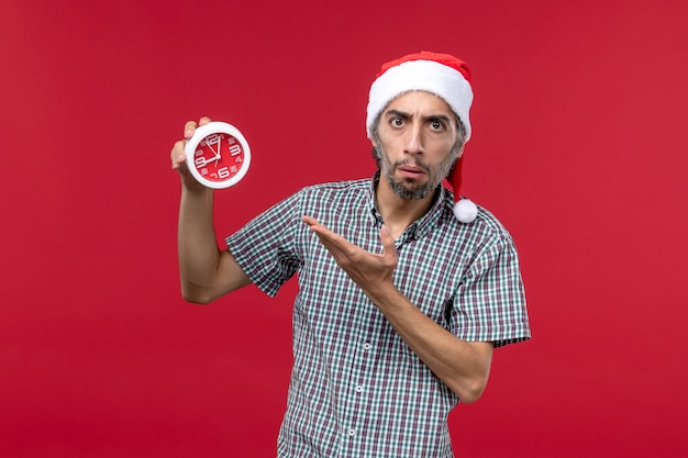 Free photo front view young male holding round clocks on red desk