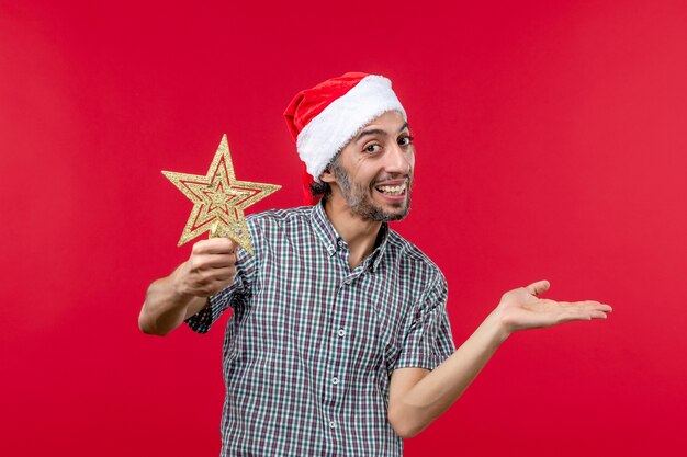 Front view of young male holding star toy on red