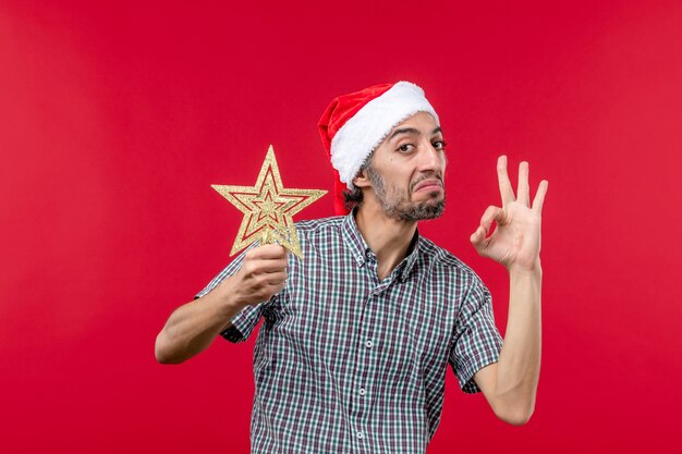 Front view of young male holding star toy on red