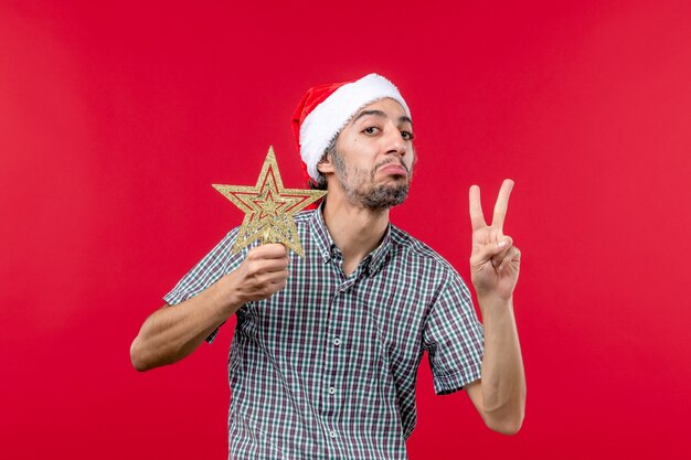 Front view of young male holding star toy on red