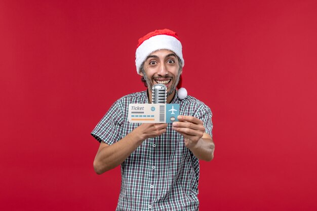 Front view young male holding ticket and mic on red background