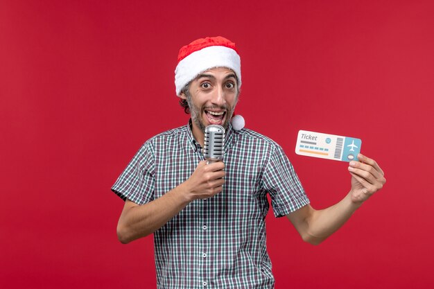 Front view young male holding ticket and mic on red background