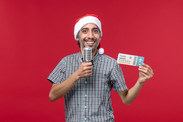 Front view young male holding ticket and mic on red background