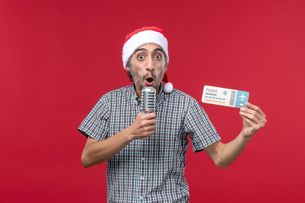 Front view young male holding ticket and mic on red desk