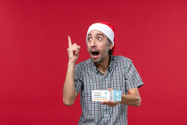 Front view young male holding ticket on red background