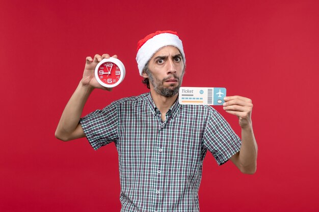 Front view young male holding ticket with clock on red background