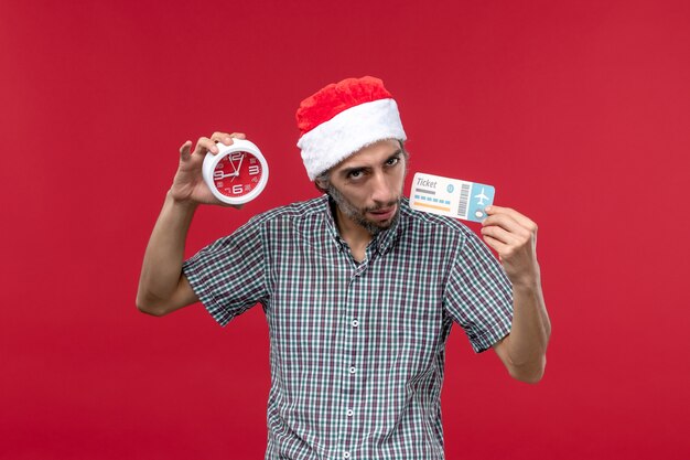 Front view young male holding ticket with clock on red background