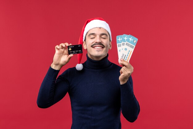 Front view young male holding tickets and bank card on red background