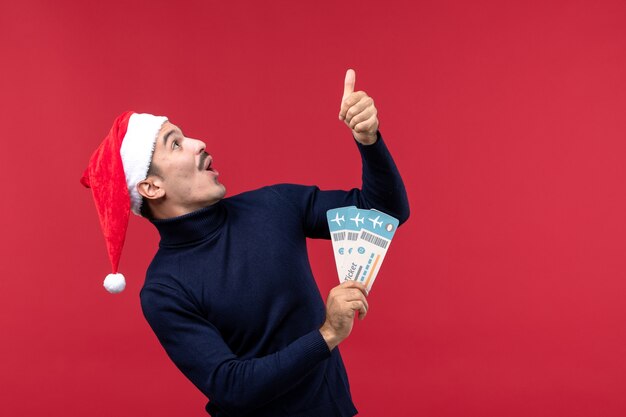 Free photo front view young male holding tickets on red background