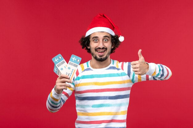赤い壁の男性の休日新年赤でチケットを保持している正面図若い男性