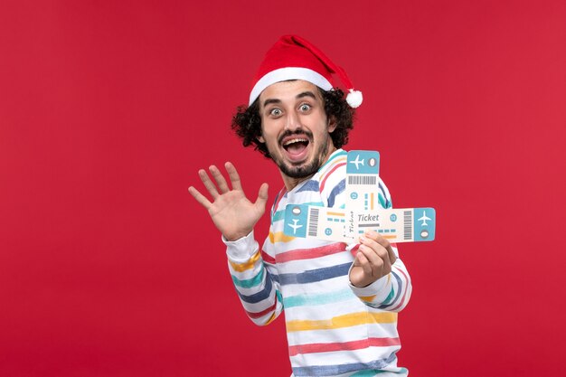 Front view young male holding tickets on red wall plane flight new year red emotions