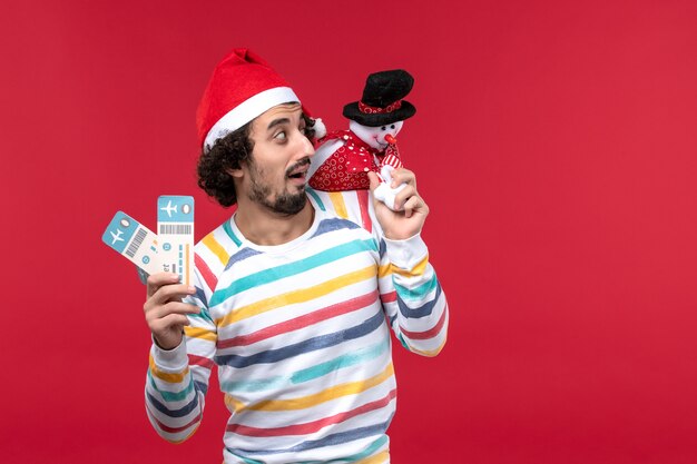 正面図若い男性がチケットとおもちゃを持っている明るい赤い壁の男性赤い休日新年