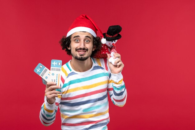 Front view young male holding tickets and toy on red desk male red holiday new year