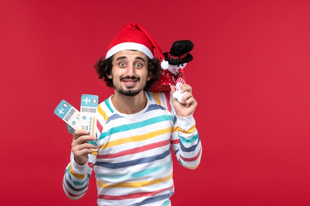正面図若い男性がチケットと赤い机の上のおもちゃを保持している男性赤い休日新年