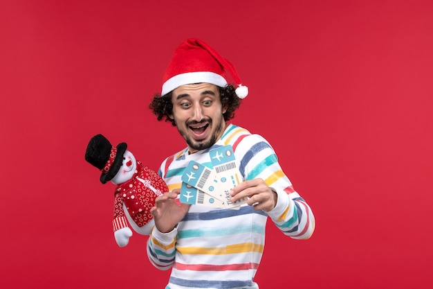 Front view young male holding tickets and toy on red wall male red holidays new year