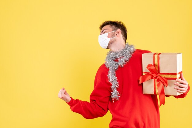 Front view young male holding xmas present in sterile mask