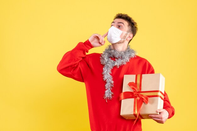 無菌マスクに存在するクリスマスを保持している正面図若い男性