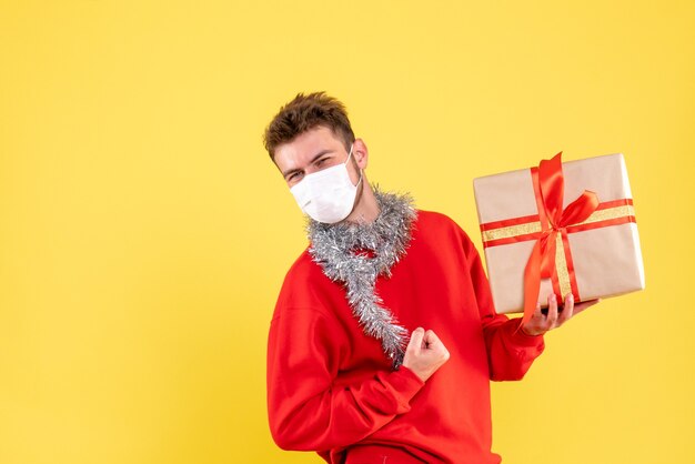 Front view young male holding xmas present in sterile mask