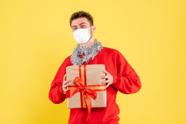 Front view young male holding xmas present in sterile mask