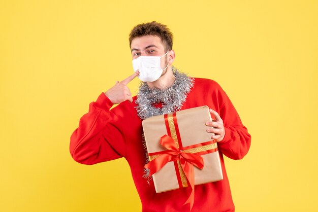 Front view young male holding xmas present in sterile mask