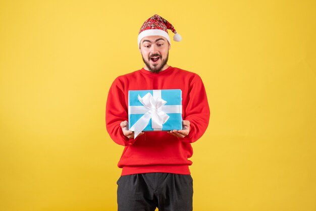 Free photo front view young male holding xmas present on yellow background