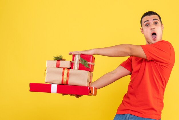 Front view young male holding xmas presents on yellow background