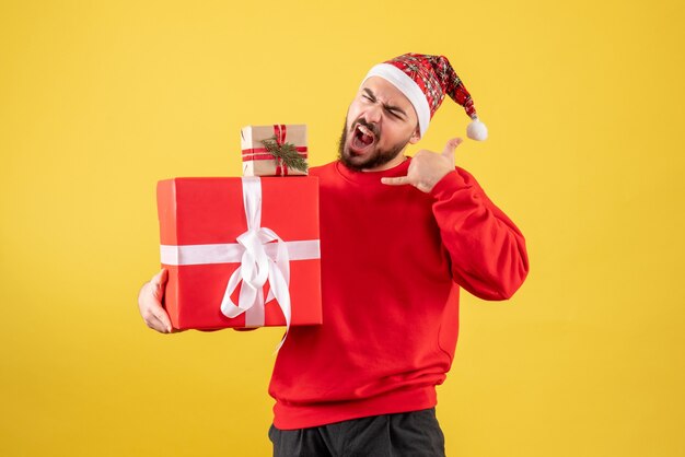 Front view young male holding xmas presents on yellow background