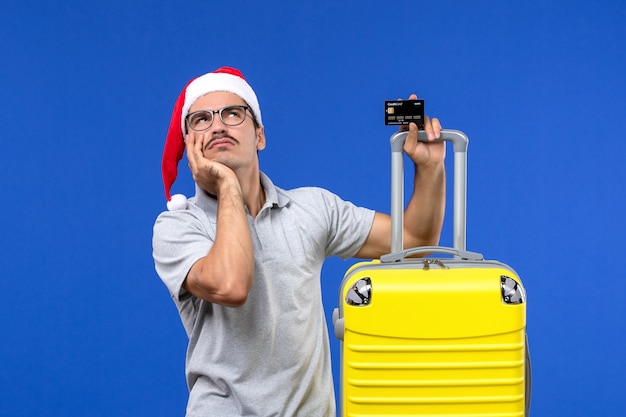 Front view young male holding yellow bag bank card on blue wall trip emotions vacation