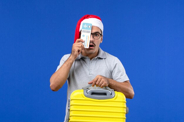 Front view young male holding yellow bag and tickets on blue background flight vacation planes