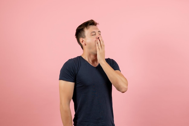 無料写真 ピンクの背景にあくびをしている紺色のシャツの正面図若い男性