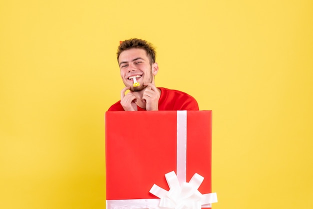 Бесплатное фото Вид спереди молодой мужчина в красной рубашке, сидящий внутри подарочной коробки