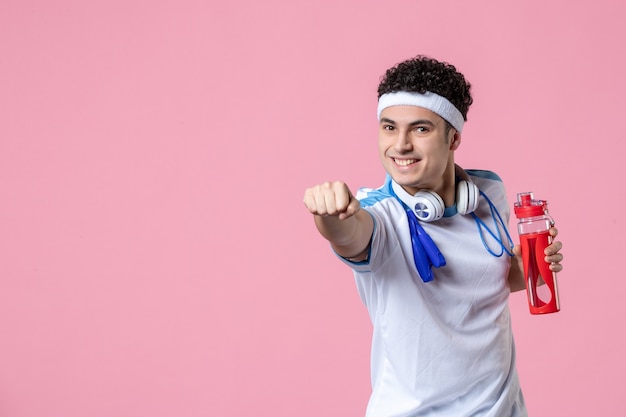 Бесплатное фото Вид спереди молодого мужчины в спортивной одежде со скакалкой на шее розовая стена
