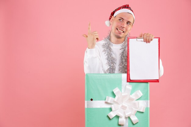 Front view young male inside present holding file notes on pink background