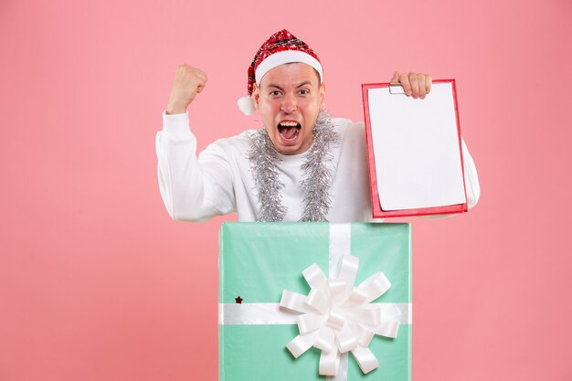 Front view young male inside present holding file notes on pink background