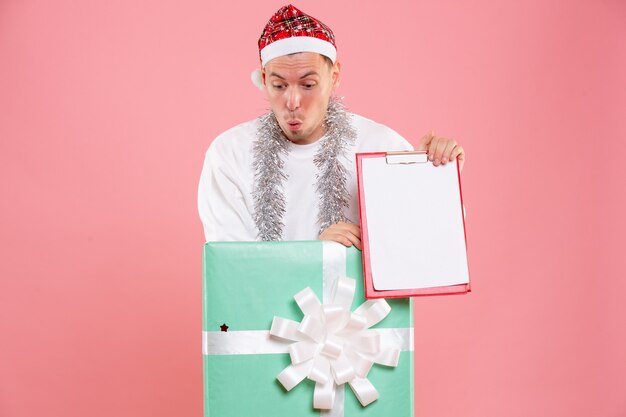 Front view young male inside present holding file notes on pink background