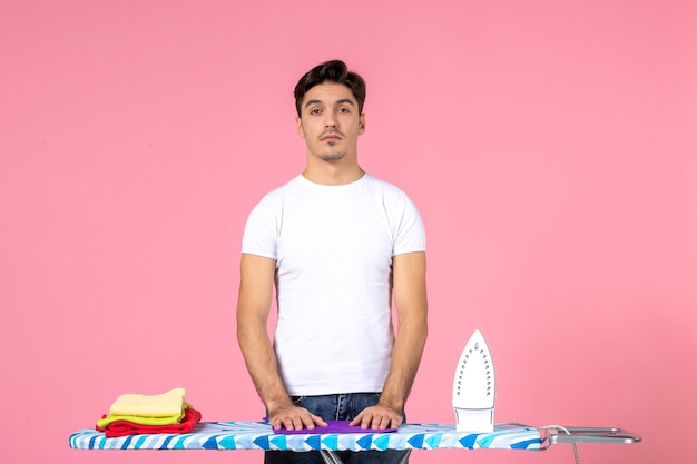 Free photo front view young male behind ironing board on pink