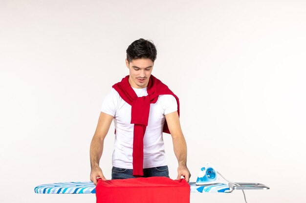 흰색 바탕에 다림판 뒤에 있는 전면 보기 젊은 남성 세탁소 집 색상 작업 남자 가사 깨끗한 감정