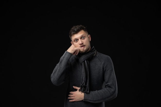 Front view of young male in jersey with scarf on black wall