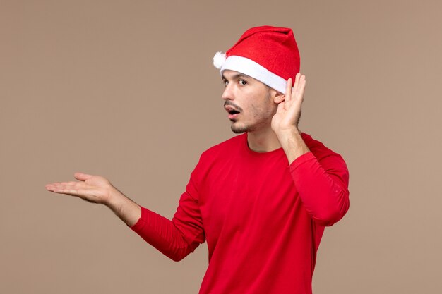 Front view young male listening closely on brown background christmas emotion holiday