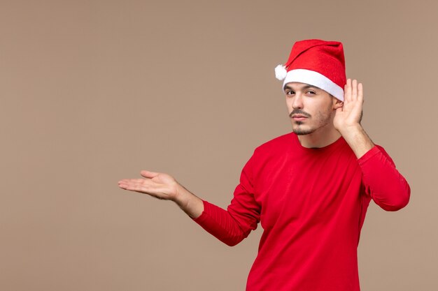 正面図茶色の机のクリスマスの感情の休日をよく聞いている若い男性