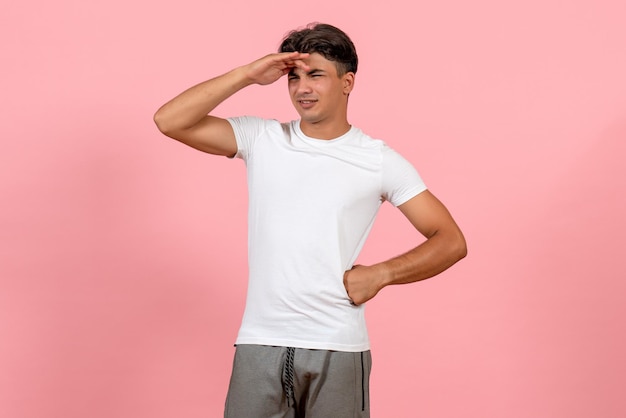 Front view young male looking at distance on pink background