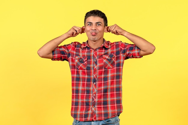 Front view young male making funny faces on yellow background