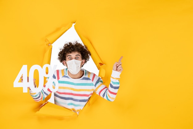 Free photo front view young male in mask holding writing on yellow virus pandemic color shopping health photo sale