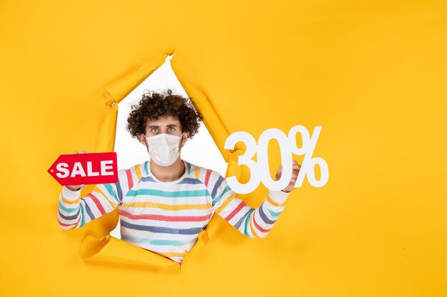 Front view young male in mask holding on yellow pandemic color shopping red health photo virus sale