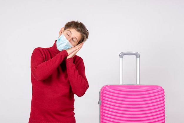 Front view of young male in mask with pink bag sleeping on white wall