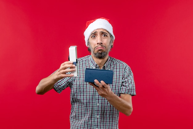 Free photo front view of young male opening christmas present on red