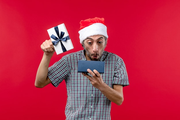 赤でクリスマスプレゼントを開く若い男性の正面図